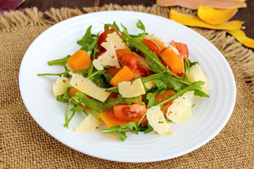 Dietary salad with pumpkin, fresh tomatoes, arugula and Parmesan.