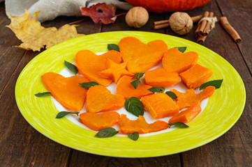 Honey Baked slices of pumpkin in the form of various figures, decorating mint leaves. Lovely snacks for a party (Halloween). Children's menu.