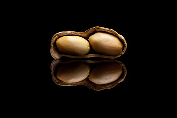 One peeled peanut isolated on black reflective background