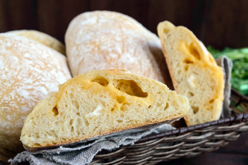 Ciabatta with cheese stuffing - freshly baked Italian white bread on a dark wooden background. For the preparation of sandwiches.