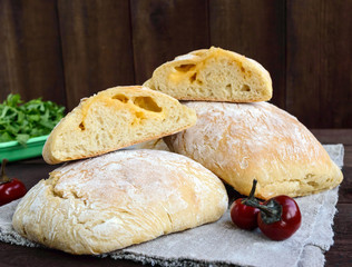 Ciabatta with cheese stuffing - freshly baked Italian white bread on a dark wooden background. For the preparation of sandwiches.
