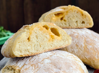 Ciabatta with cheese stuffing - freshly baked Italian white bread on a dark wooden background. For the preparation of sandwiches.