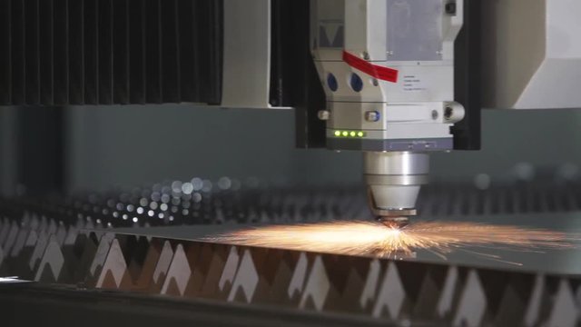 Laser cutting of flat sheet metal steel material with sparks.