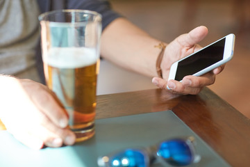 close up of man with smartphone and beer at pub