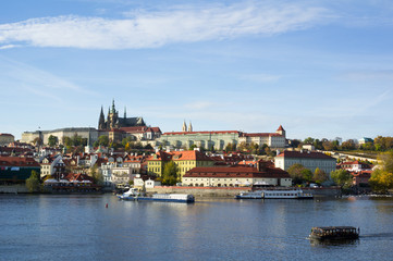 Fototapeta na wymiar Prague Castle, Hradcany, Prague, Czech Republic / Czechia - panorama of historical part of the city. Dominant towers of Saint Vitus Cathedral. Boats with tourists on the Vltava river