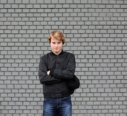 Portrait of attractive teenage boy standing  in front of a brick wall.
