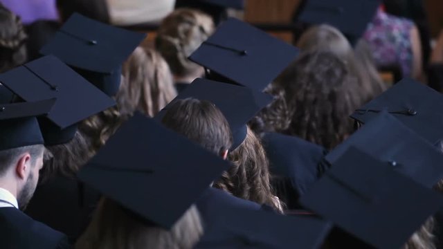 Many graduates wearing academic caps, higher education statistics background