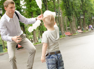 Fototapeta premium baby boy eating cotton candy with his father