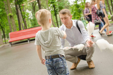 Fototapeta premium baby boy eating cotton candy with his father