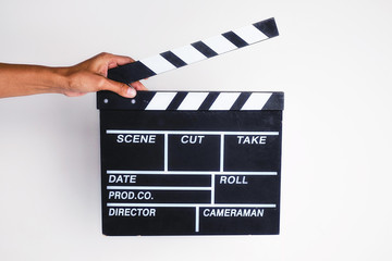 closeup of a young man about to clap a traditional wooden clapperboard against background