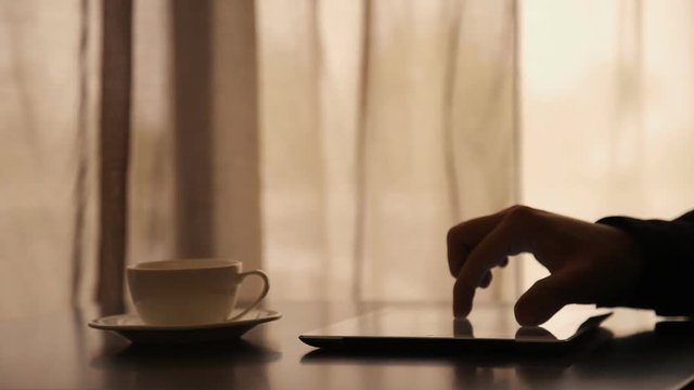 Man Using Tablet PC and Drinking Coffee in Cafe