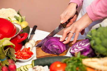 Housewife cutting red cabbage on slices in the kitchen