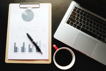 Office desk table with new modern computer, analysis chart, pen, cup of coffee and. Top view with copy space (selective focus)