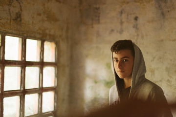 Hooded teenage boy in an abandoned house