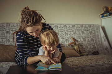 Naklejka premium young pregnant mother and son reading a book, lifestyle,