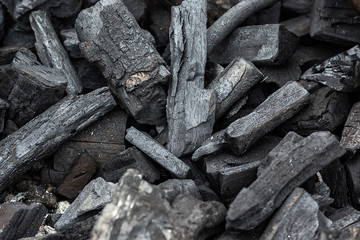 Black charcoal texture background. Natural wood charcoal, traditional charcoal or hard wood charcoal. Pile of charcoal. Details on the surface of charcoal.
