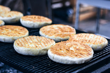 Georgian traditional dish khachapuri, pastry flat cake cheese-filled bread fried on the grill, BBQ. Fresh hot tasty street food in the market. Cooking food. Preparation dish of Middle Eastern cuisine.