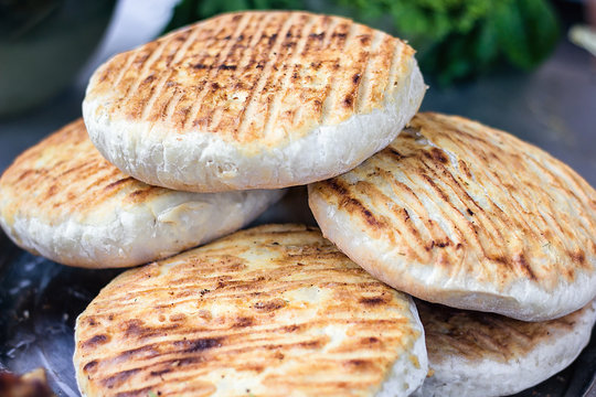 Georgian traditional dish khachapuri, pastry flat cake cheese-filled bread fried on the grill, BBQ. Fresh hot tasty street food in the market. Cooking food. Preparation dish of Middle Eastern cuisine.