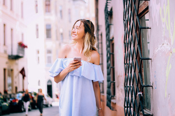 
beautiful blonde petushustvet and walks around the city in white dress and with a backpack, looking for a route to the mobile phone via the application