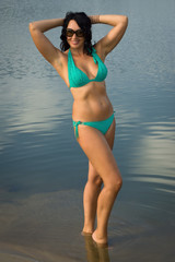 Obraz premium Beautiful woman in bikini on the beach by the lake