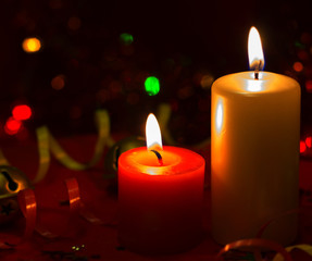 Christmas and New Year`s festive evening burning candle bokeh image. Greeting card dark lights Background concept with holiday tinsel, twisted ribbons and copyspace place for text or logo.