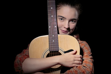 beautiful woman hugging her guitar, isolated on black