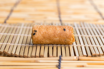 Crispy roll with dried shredded pork on a bamboo pad.