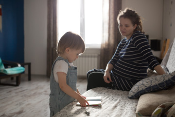 young pregnant mother and son reading a book, lifestyle,