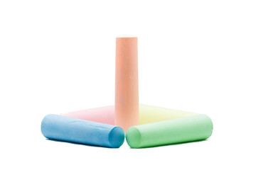 Orange colored chalk standing inside 4 colored chalks on white b