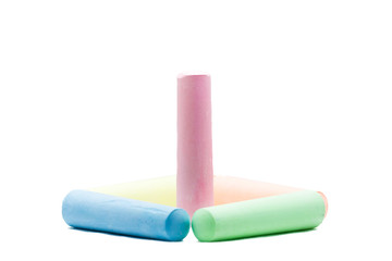 Pink colored chalk standing inside 4 colored chalks on white bac