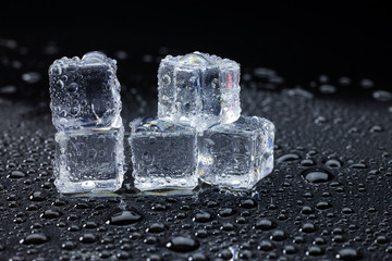 Wet ice cubes and water drop on black background.