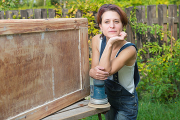 Woman with polishing machine is posing outdoors during furniture