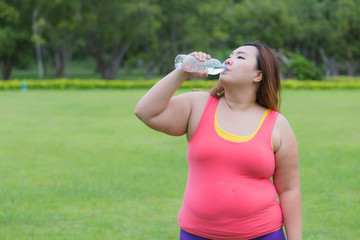 Beautiful fat woman drinking water after finish her workout.