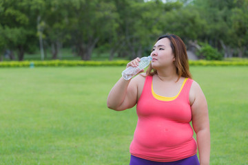 Beautiful fat woman drinking water after finish her workout.