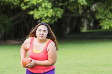 Beautiful fat woman playing american football in the park.