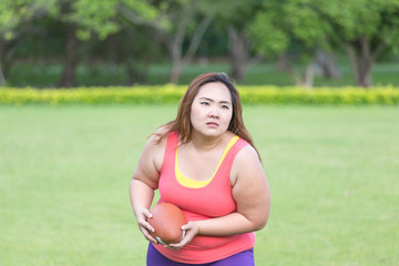 Beautiful fat woman playing american football in the park.