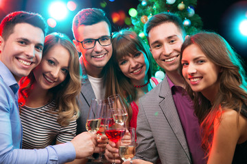 Young friends touching the glasses with each other