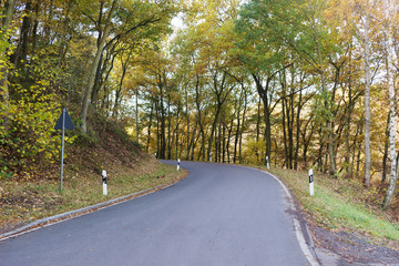 Narrow empty asphalt road with sharp curve leads into the mountains