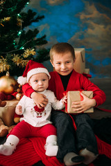 Portrait of happy children with Christmas gift boxes and decorations. Two kids having fun at home
