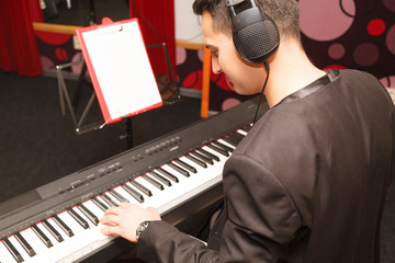 young handsome man playing on a synthesizer