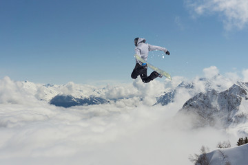 Naklejka na ściany i meble Snowboard rider jumping on mountains. Extreme snowboard sport.