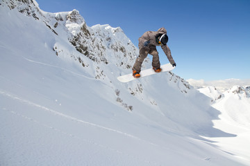 Naklejka na ściany i meble Snowboard rider jumping on mountains. Extreme snowboard sport.