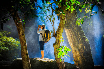 traveler use binoculars in water fall, water spray spreading aro