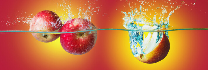 Apples with water splash over bright yellow-red background