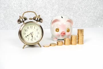 piggy bank with gold coins stack and alarm clock on white backgr