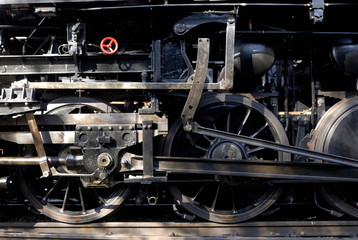 Steam locomotive wheels and rods closeup. Detail of mechanical parts, wheels and equipment of the train.