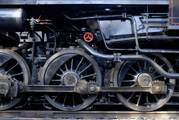 Obraz premium Steam locomotive wheels and rods closeup. Detail of mechanical parts, wheels and equipment of the train.
