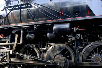 Steam locomotive wheels and rods closeup. Detail of mechanical parts, wheels and equipment of the train.