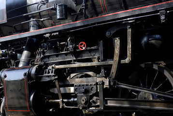 Steam locomotive wheels and rods closeup. Detail of mechanical parts, wheels and equipment of the train.