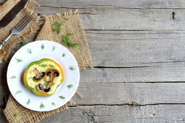 Homemade omelette with mushrooms in green pepper. Original eggs omelette on a plate, fork and knife on old wooden background with copy space for text. Top view
